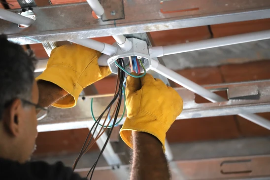 &Eacute;lectricien installant des c&acirc;bles dans un b&acirc;timent en construction
