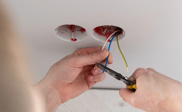 Main en gros plan d'un &eacute;lectricien tenant une prise de prise &eacute;lectrique pour r&eacute;paration ou entretien et fixation dans la salle de bureau