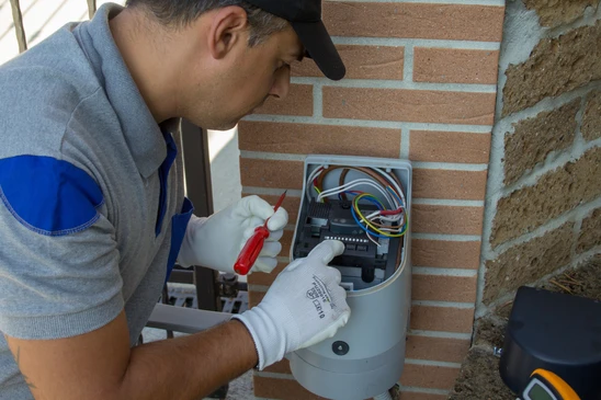 Technicien &eacute;lectricien effectuant la r&eacute;paration et la programmation d'une fiche technique du moteur d'une porte d'entr&eacute;e automatique