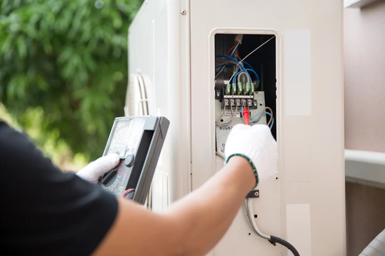 Technicien &eacute;lectricien en intervention ext&eacute;rieure utilisant un multim&egrave;tre pour diagnostiquer un tableau &eacute;lectrique ouvert