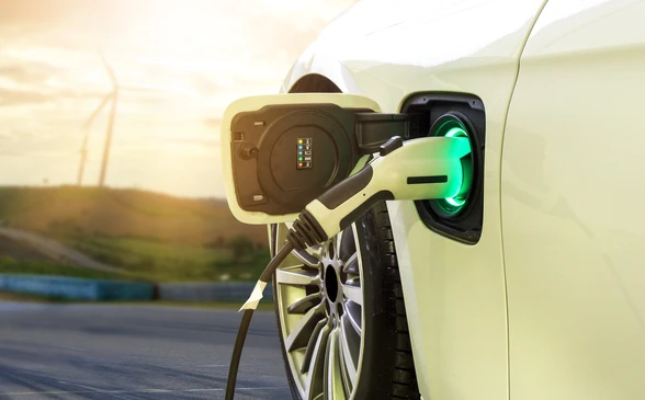 Scène extérieure en fin de journée avec véhicule électrique blanc en cours de recharge