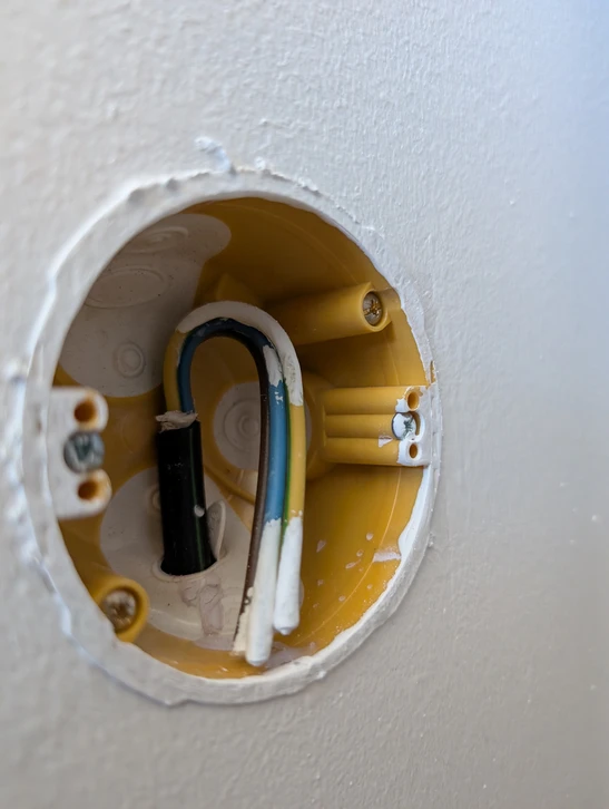 Technicien en combinaison de s&eacute;curit&eacute; et casque blanc travaillant sur installation &eacute;lectrique r&eacute;sidentielle